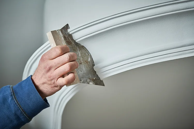 Daniel Reimertshofer von Eifel Putz und Stuck arbeitet präzise und nach Kundenwunsch an einer Stuckleiste in einem Haus in Schleiden.